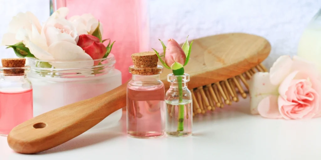 Rose water for hair care with a wooden brush and pink bottles - is rose water good for hair?