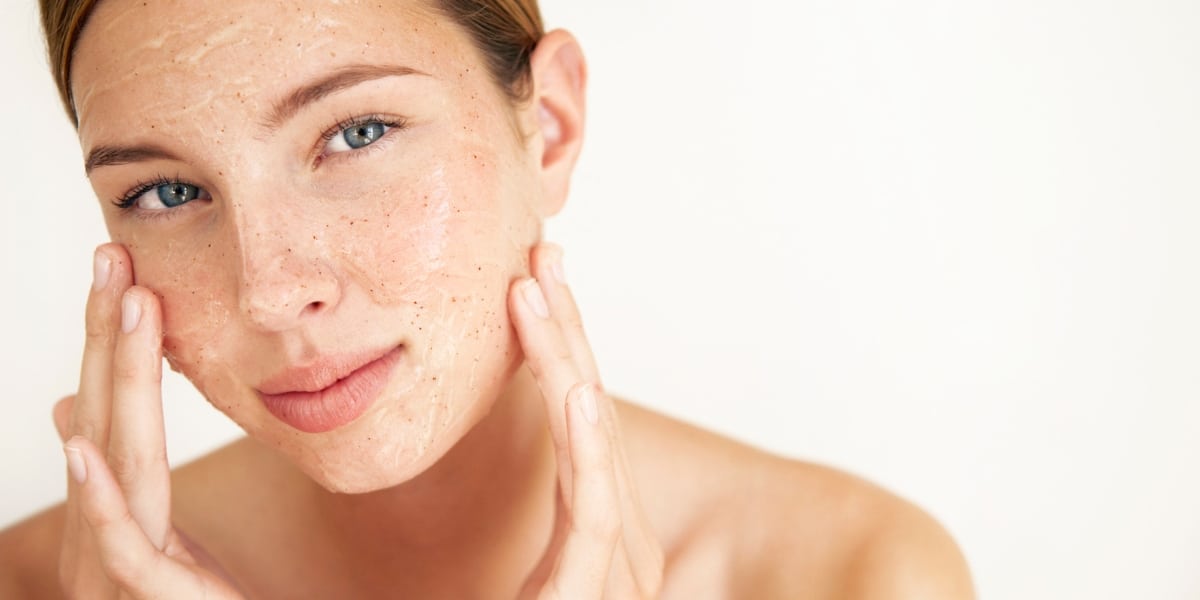 Woman using a natural exfoliator for oily skin, gently applying a scrub to her face.