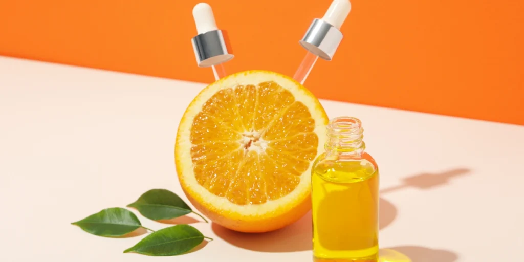 a bottle of essential oil next to an orange