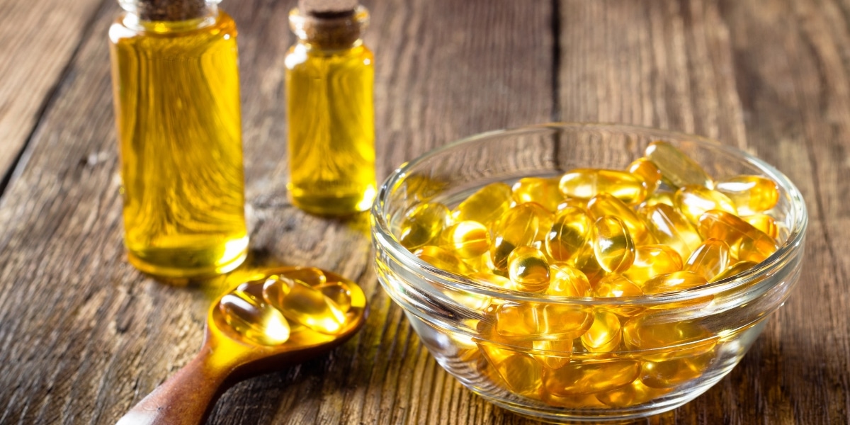 Golden fish oil for hair capsules and bottles showcasing the Omega 3 benefits for hair on a wooden surface.