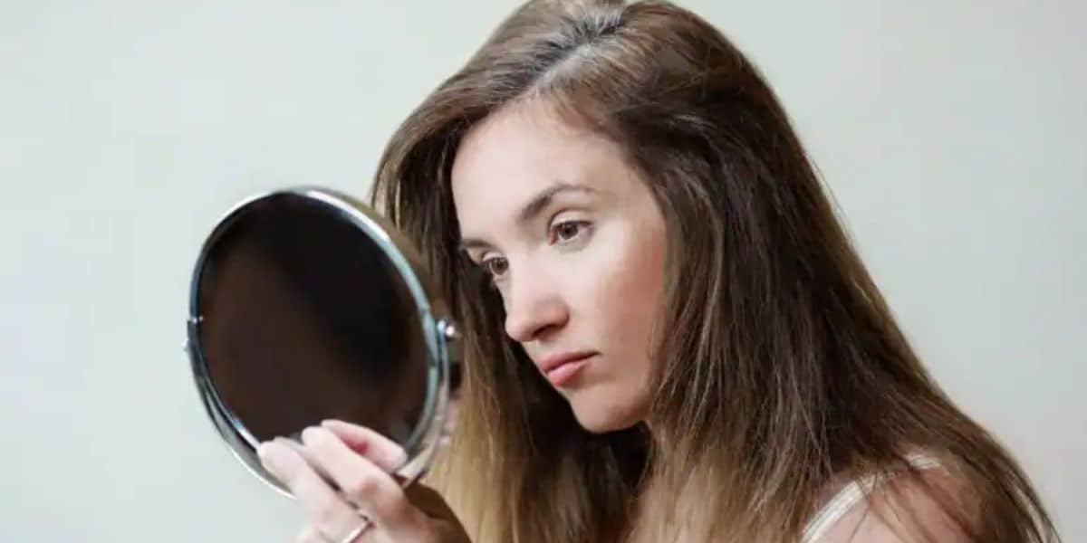 Young woman looking at her hair for solutions to prevent white hair from spreading, understanding causes and remedies for white hair at early age.